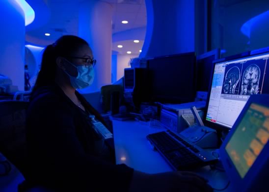 Woman with a surgical mask working on a medical project on her computer.