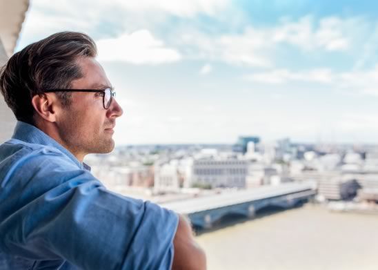 Man on a balcony looking out at a city
