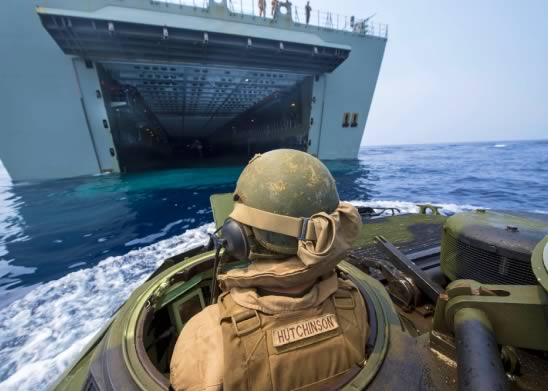 Man on a boat in the ocean approaching a Navy ship