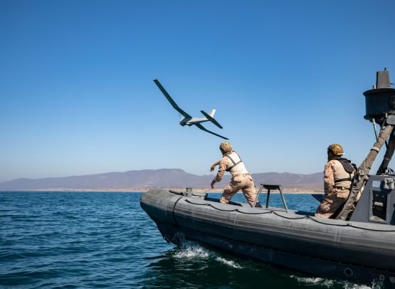 Decorative image of a boat in the sea with a plane flying above it.