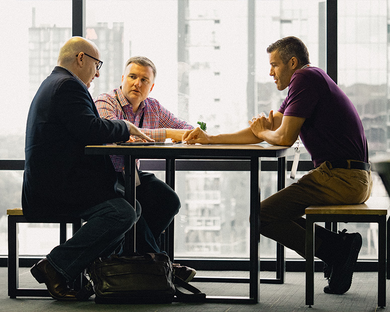 Three people discuss business at an office